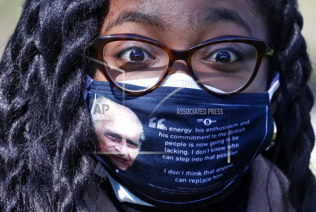 Frank Augstein A woman wears a face covering with a picture of the Duke of Edinburgh as he walks along the Long Walk in Windsor, Saturday, April 17, 2021. Britain's Prince Philip, husband of Queen Elizabeth II, died Friday April 9, aged 99, his funeral service takes place at Windsor Castle in St George's Chapel. (AP Photo/Frank Augstein)
