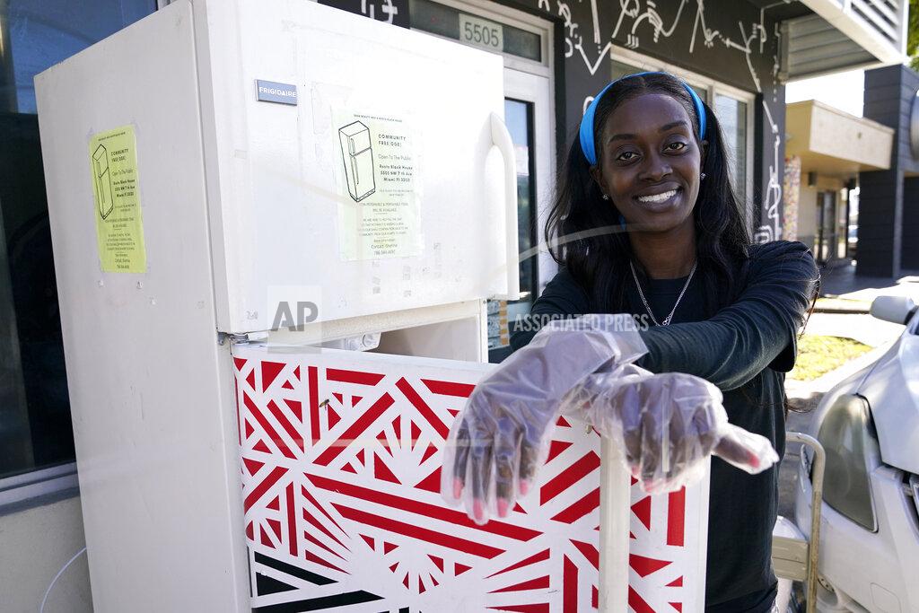 Lynne Sladky Sherina Jones poses with one of her community refrigerators, Wednesday, Dec. 9, 2020, in the Liberty City neighborhood of Miami. Jones offers free food for the community from a stocked community refrigerator called the Village Freedge. When one of the refrigerators was stolen just before Thanksgiving, the community and friends came together to help to purchase a new one. Jones also provides hot food and distributes numerous food pantry items. She has applied for non-profit status and is transitioning to become a food bank. (AP Photo/Lynne Sladky)