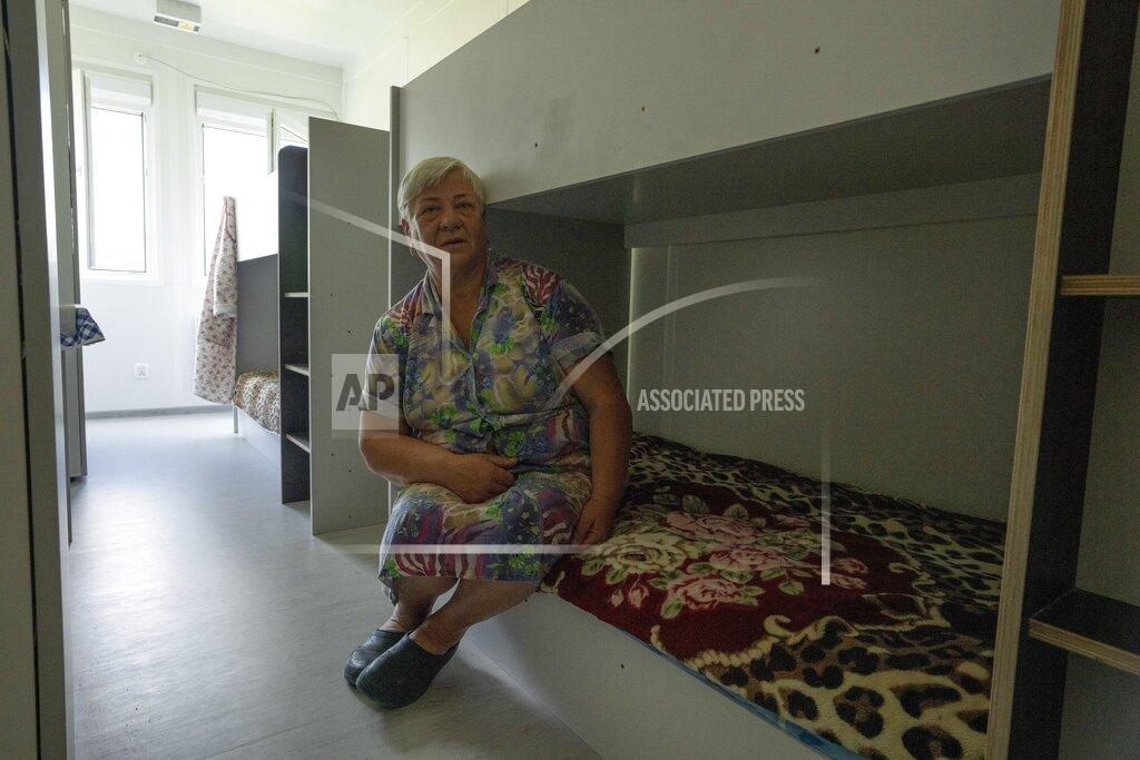 Nariman El-Mofty 64-year-old Tetiana Solohub sits on her bed inside a trailer set up for temporary housing for people who lost their homes destroyed from Russian aerial bombs, in Borodyanka, Kyiv region, Ukraine, Tuesday, June 28, 2022. Solohub shares a small, narrow room with plastic walls with two other people. There aren't many things on her shelf. She didn't have a chance to rescue her belongings. Because of the summer heat, it is difficult for her to stay in her makeshift home all day. So she often goes to rest in a small garage with metal walls and no windows near her home. (AP Photo/Nariman El-Mofty)