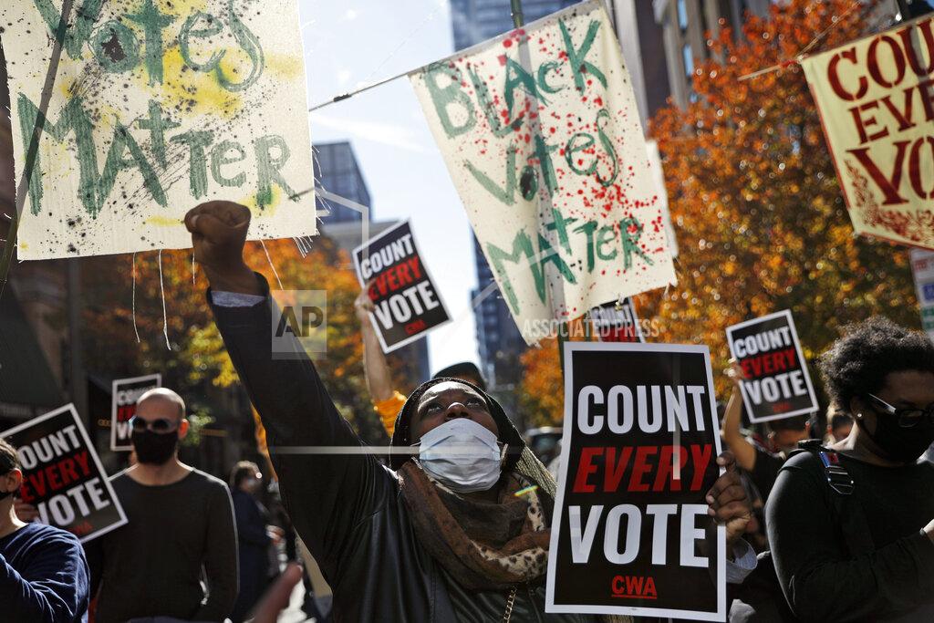 Rebecca Blackwell Zhanon Morales, 30, of Philadelphia, raises her fist as demonstrators call for all votes be counted during a rally outside the Pennsylvania Convention Center, Thursday, Nov. 5, 2020, in Philadelphia, as vote counting in the general election continues. (AP Photo/Rebecca Blackwell)