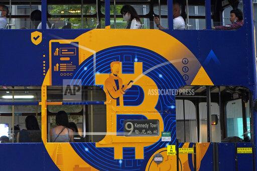 FILE - This May 12, 2021, file photo shows an advertisement for the cryptocurrency Bitcoin displayed on a tram in Hong Kong. Cryptocurrencies have surged to nearly $2.5 trillion in total value, rivaling the size of G7 economies like Canada’s and Italy’s, with more than 200 million users. At that size, it’s simply too large for the financial establishment to ignore. Firms that cater to the world’s wealthiest families are increasingly putting some of their fortunes into crypto. Hedge funds are trading Bitcoin, which has big-name banks starting to offer them services around it. And in the latest milestone for the industry, an easy-to-trade fund tied to Bitcoin began trading on Tuesday, Oct. 19, 2021. (AP Photo/Kin Cheung, File)