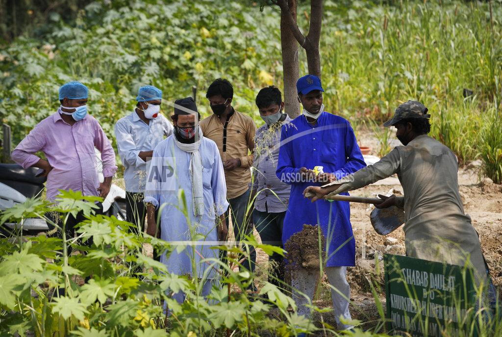 Manish Swarup Relatives and health workers pay their respects as the body of a three-month-old COVID-19 victim is buried in New Delhi, India, Wednesday, Sept. 16, 2020. India's total of coronavirus infections passed 5 million Wednesday, still soaring and testing the feeble health care system in tens of thousands of impoverished towns and villages. (AP Photo/Manish Swarup)