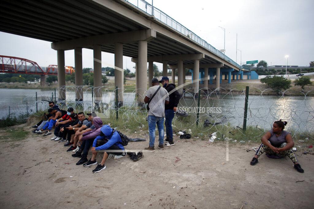 Dario Lopez-Mills Ana Rita Pinales, 28, from the Dominican Republic, right, and other migrants who had crossed the Rio Grande river into the U.S., are under custody of National Guard members as they await the arrival of U.S. Border Patrol agents in Eagle Pass, Texas, Friday, May 20, 2022. The Eagle Pass area has become increasingly a popular crossing corridor for migrants, especially those from outside Mexico and Central America, under Title 42 authority, which expels migrants without a chance to seek asylum on grounds of preventing the spread of COVID-19. A judge was expected to rule on a bid by Louisiana and 23 other states to keep Title 42 in effect before the Biden administration was to end it Monday. (AP Photo/Dario Lopez-Mills)