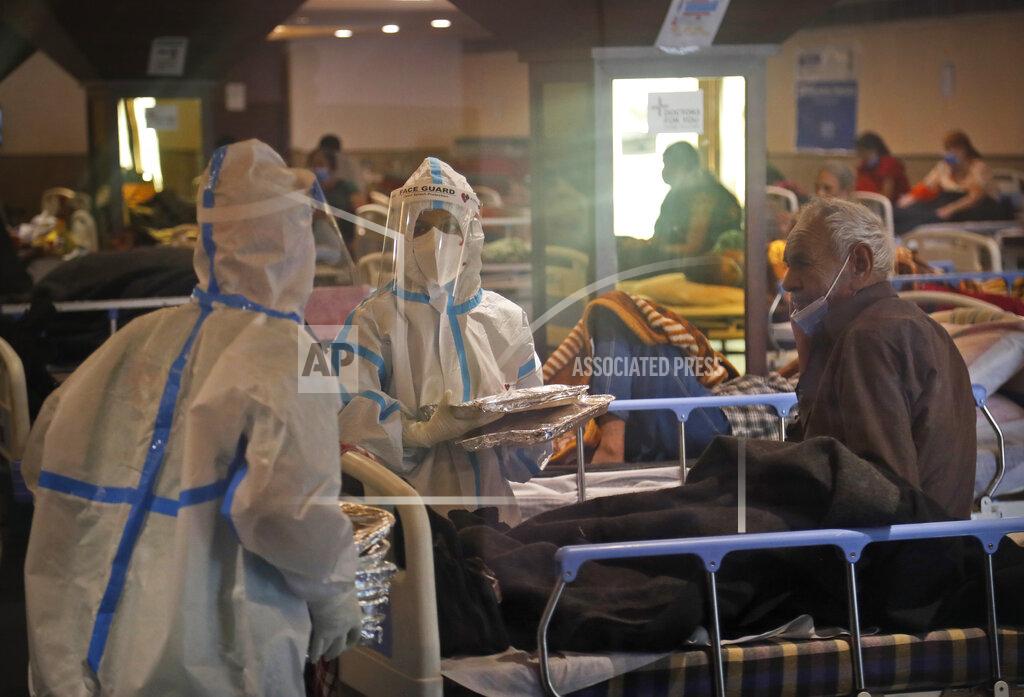 Manish Swarup A health worker distributes food packets inside a quarantine center for COVID-19 patients, in New Delhi, India, Monday, April 19, 2021. India's health system is collapsing under the worst surge in coronavirus infections that it has seen so far. (AP Photo/Manish Swarup)