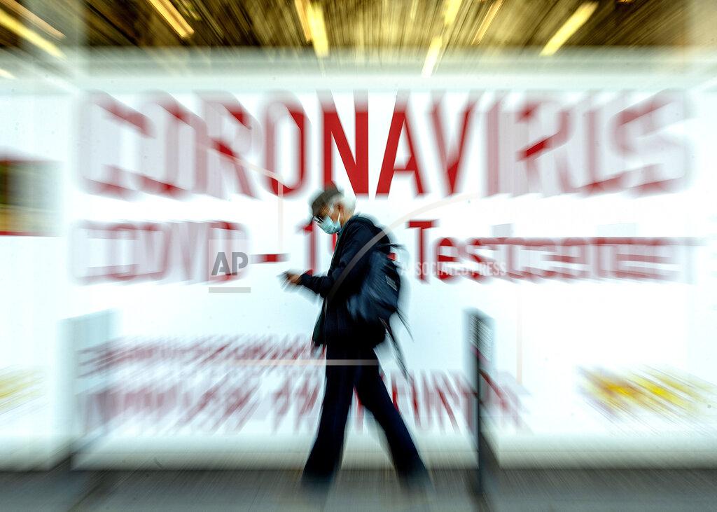 Michael Probst In this Feb.25, 2021 file photo a man walks by a sign in the window of a Coronavirus testing center in Frankfurt, Germany. (AP Photo/Michael Probst, file)