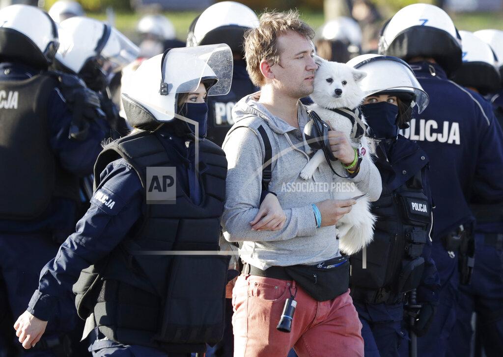 Czarek Sokolowski Police detain a man with a dog, in Warsaw, Poland, Saturday, Oct. 24, 2020. The man was among protesters angry at new restrictions aimed at fighting the coronavirus pandemic. The clashes come amid rising social tensions and as new restrictions just short of a full lockdown took effect Saturday.(AP Photo/Czarek Sokolowski)