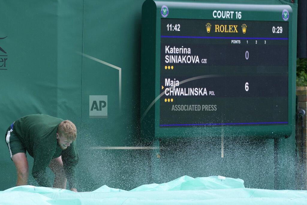 Kirsty Wigglesworth A member of ground staff shakes water off the covers during a rain delay on day one of the Wimbledon tennis championships in London, Monday, June 27, 2022. (AP Photo/Kirsty Wigglesworth)