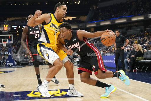 Miami Heat guard Kyle Lowry, right, drives around Indiana Pacers guard Malcolm Brogdon during the first half of an NBA basketball game in Indianapolis, Friday, Dec. 3, 2021. (AP Photo/AJ Mast)