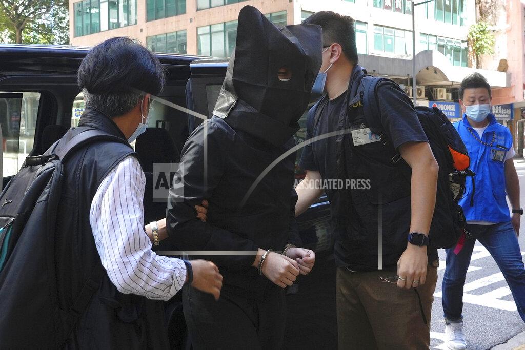 Vincent Yu A hooded suspect is accompanied by police officers to search evidence at office in Hong Kong Thursday, July 22, 2021. Hong Kong's national security police on Thursday arrested five people from a trade union of the General Association of Hong Kong Speech Therapists on suspicion of conspiring to publish and distribute seditious material, in the latest arrests made amid a crackdown on dissent in the city. (AP Photo/Vincent Yu)