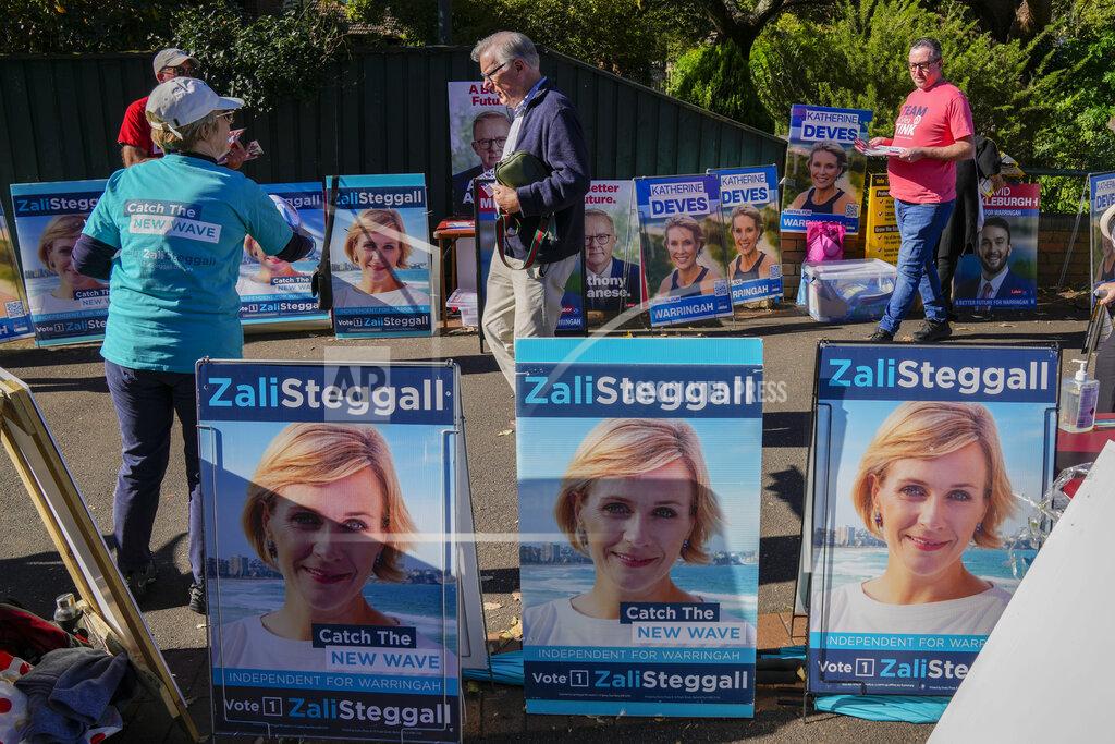 Mark Baker A volunteer hands out "how to vote cards" as voters walk past billboards of Independent candidate Zali Steggall outside a polling booth in her electorate of Warringah in Sydney, Australia on May 17, 2022. Australia's government, considered a laggard on combating climate change, faces a new threat in the form of highly-organized and well-funded independent election candidates who demand deeper cuts on greenhouse gas emissions. (AP Photo/Mark Baker)
