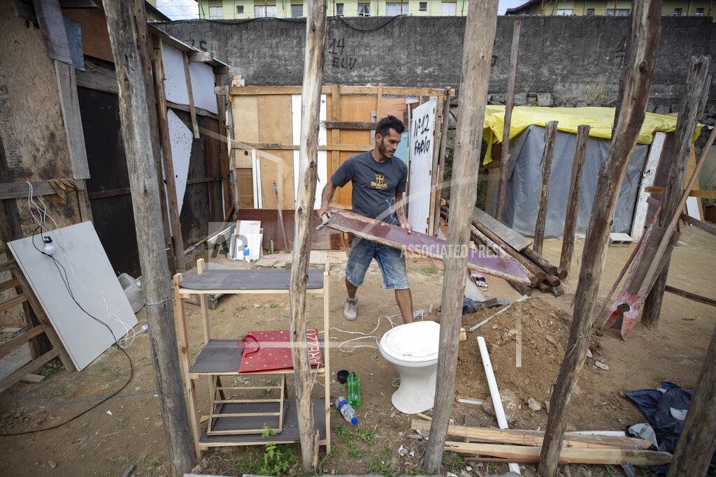 Andre Penner FILE - In this May 15, 2021 file photo, Geovani de Souza, who lost his job as a doorman, works to help a friend build a home in the Penha Brasil favela, where families like his have started relocating during the coronavirus pandemic, in Sao Paulo, Brazil. Geovani de Souza and his pregnant wife were among the 200 families who moved in about six months ago amid the economic turmoil caused by COVID-19. (AP Photo/Andre Penner)