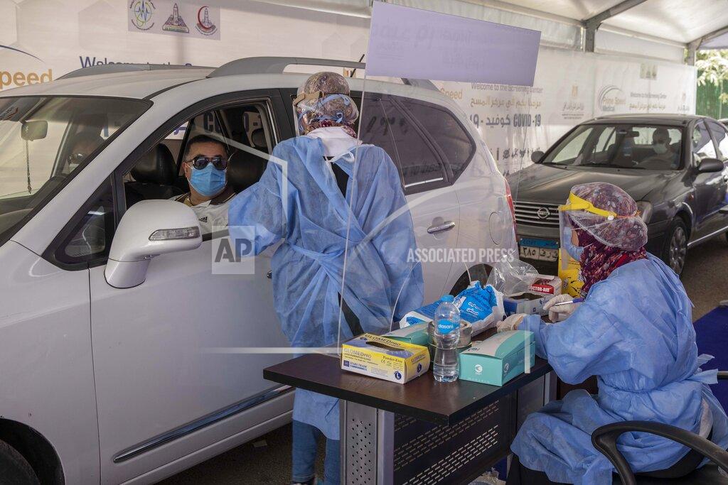 Nariman El-Mofty FILE - In this June 17, 2020 file photo, a health worker wearing protective gear prepares to take swab samples from people queuing in their cars to test for the coronavirus at a drive-through COVID-19 screening center at Ain Shams University in Cairo, Egypt. Coronavirus infections are surging in the country of 100 million, threatening to overwhelm hospitals. The government has scaled up testing within all general hospitals and ordered private companies to churn out face masks and other gear for front-line health workers. (AP Photo/Nariman El-Mofty, File)