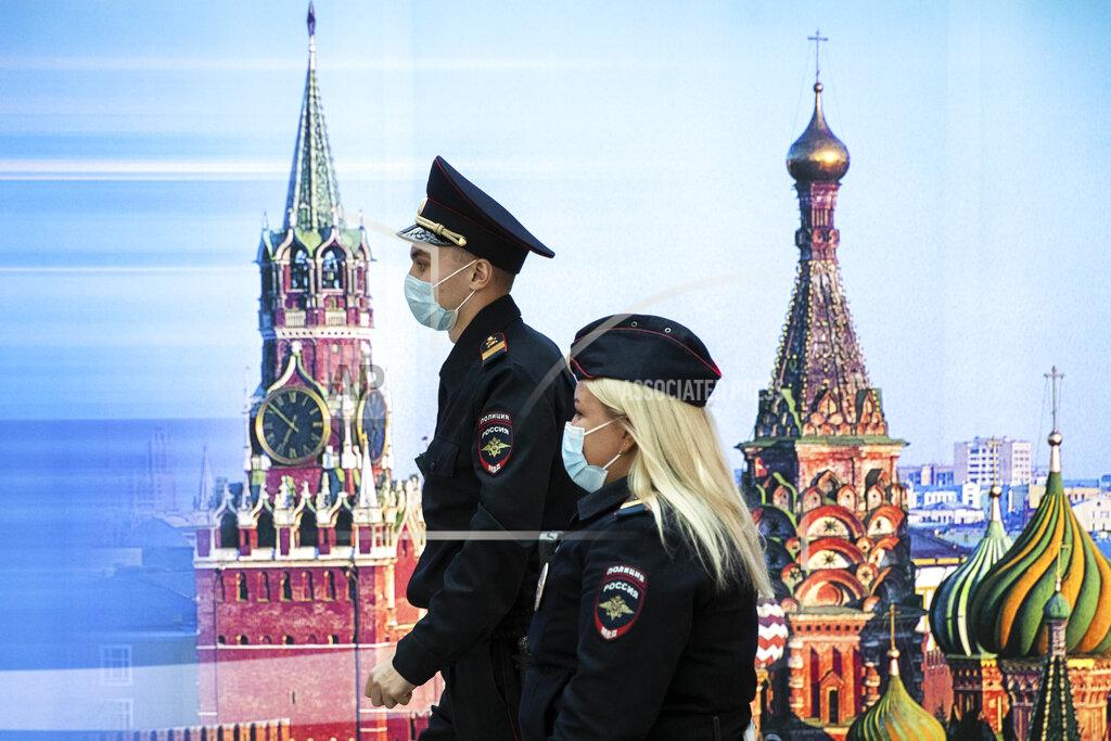 Pavel Golovkin Police officers wearing face masks to protect against coronavirus walk past a photo of Kremlin's Spasskaya Tower, left, and St. Basil's Cathedral in Sheremetyevo Airport, outside Moscow, Russia, Friday, Oct. 9, 2020. The coronavirus outbreak in Russia continues its rapid growth. (AP Photo/Pavel Golovkin)