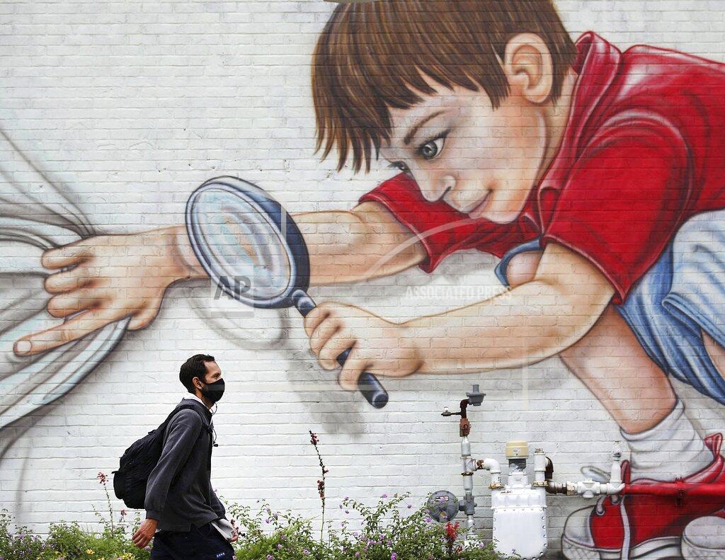 Mike Simons Johnny Lopez makes his way past a mural on the side of Hideaway Pizza on Rockford Ave. while walking home from work Thursday, Sept. 10, 2020, in Tulsa, Okla. (Mike Simons/Tulsa World via AP)