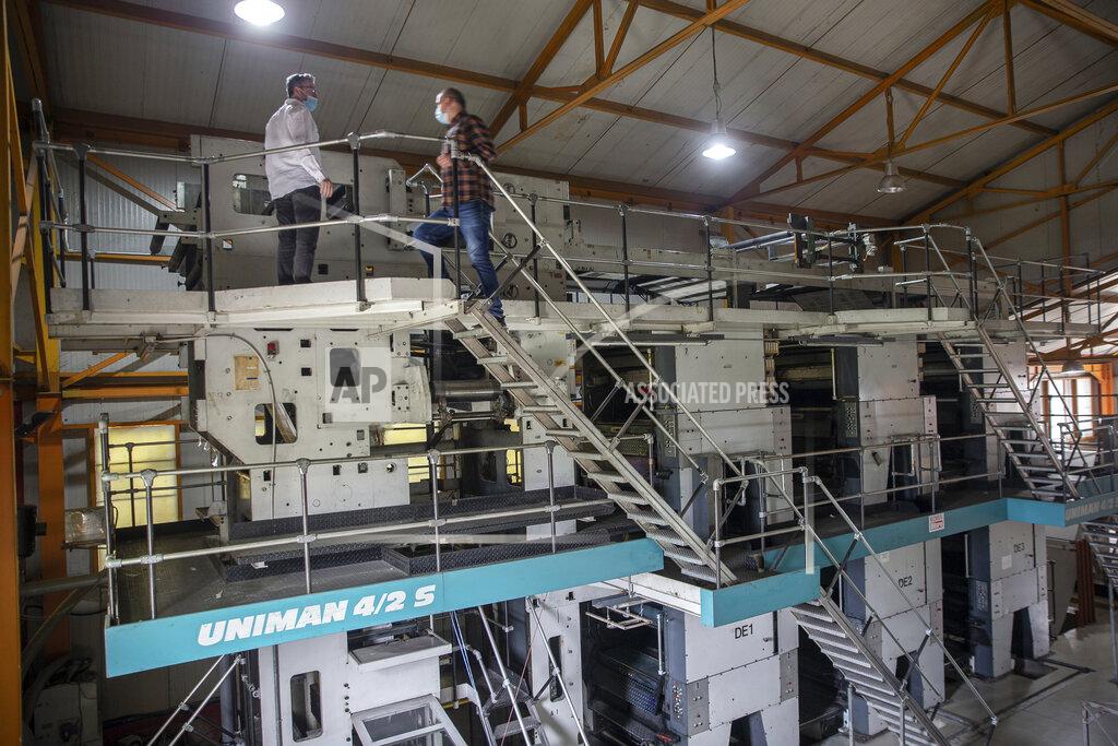 Visar Kryeziu Agron Bajrami, left, editor-in-chief of Koha daily newspaper joined by administrator of Koha printing house, Nexhmedin Berisha, stand by the rotogravure printing machine, near the capital Pristina, Wednesday, April 28, 2021. The printing presses stopped running at the start of the pandemic in Kosovo. The country's five dailies all stopped printing physical newspapers and turned into online media portals. But these do not reach all the people as before, and many fear they prioritise speed over accuracy. (AP Photo/Visar Kryeziu)