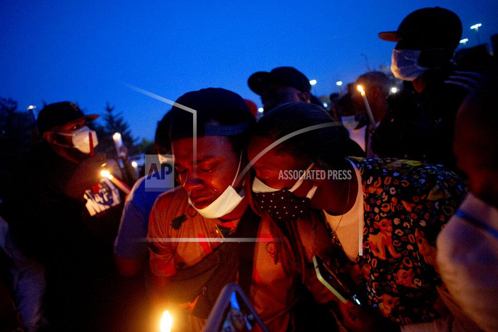 Jake May Maalik Mitchell, center left, sheds tears as he says goodbye to his father, Calvin Munerlyn, during a vigil Sunday, May 3, 2020, in Flint, Mich. Munerlyn was shot and killed Friday at a Family Dollar store in Flint. He'd worked at the store as a security guard for a little more than one year. (Jake May/The Flint Journal via AP)