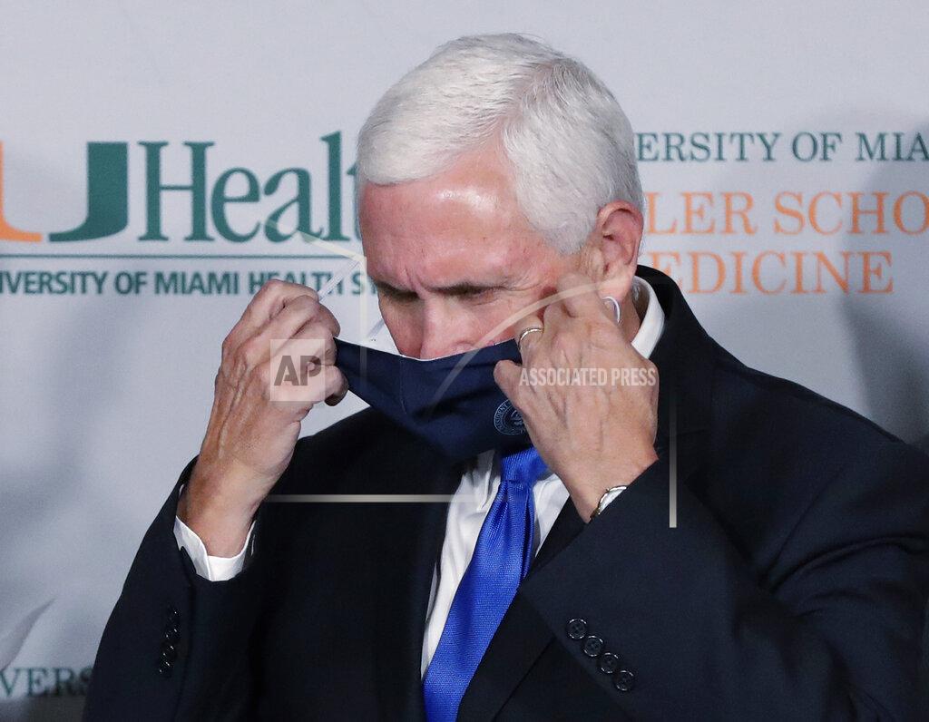 Wilfredo Lee Vice President Mike Pence takes off his mask before speaking during a news conference at the University of Miami Miller School of Medicine Don Soffer Clinical Research Center, Monday, July 27, 2020, in Miami. Pence was in Florida to mark the beginning of Phase III trials for a coronavirus vaccine. (AP Photo/Wilfredo Lee)