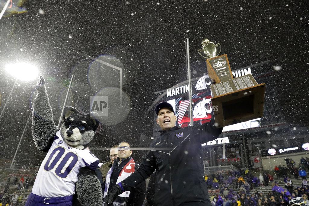 Ted S. Warren Washington coach Chris Petersen, right, holds the Apple Cup trophy as he celebrates with Harry, the Washington Huskies' mascot, after Washington defeated Washington State 28-15 in an NCAA college football game Friday, Nov. 23, 2018, in Pullman, Wash. (AP Photo/Ted S. Warren)