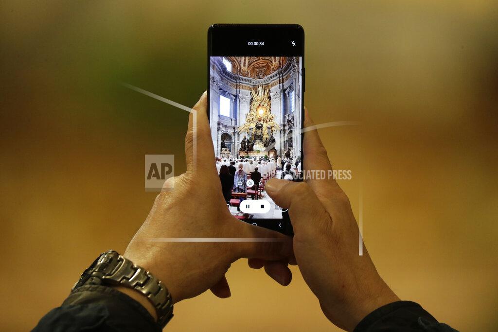 Andrew Medichini A man films a Chrism Mass celebrated by Pope Francis inside St. Peter's Basilica, at the Vatican, Thursday, April 1, 2021. During the Mass the Pontiff blesses a token amount of oil that will be used to administer the sacraments for the year. (AP Photo/Andrew Medichini, pool)