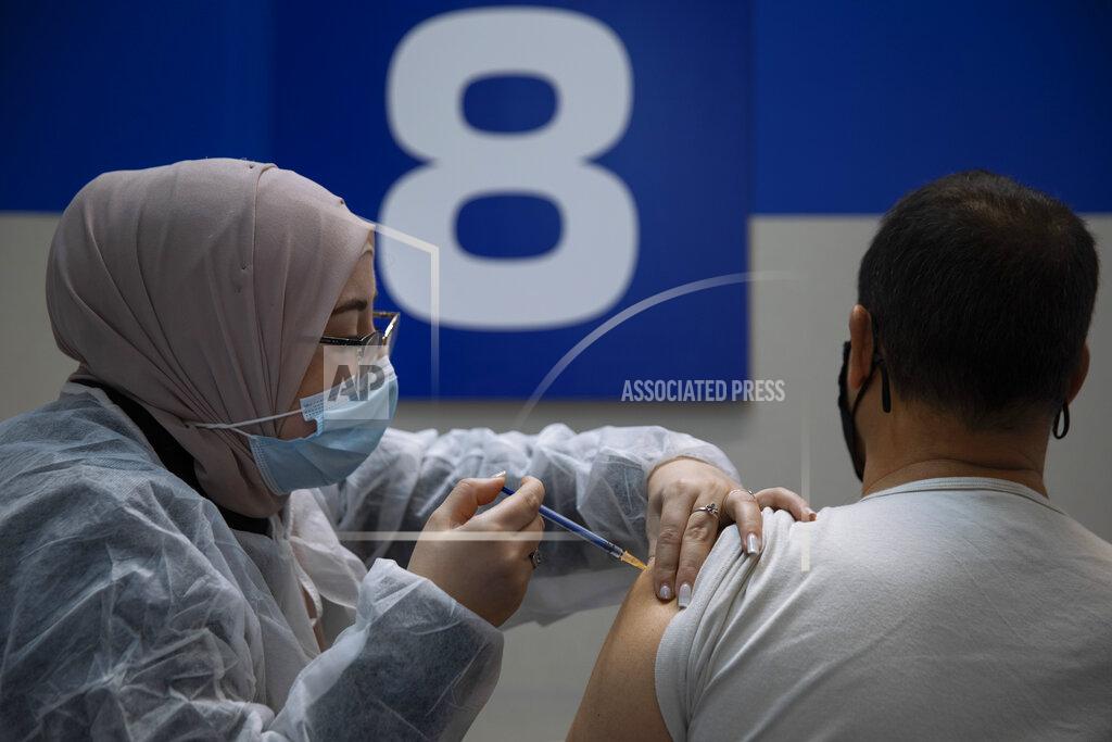 Oded Balilty An Israeli man receives his second Pfizer-BioNTech COVID-19 vaccine from a medical professional at a vaccination center set up on a mall parking lot in Givataim, Israel, during a nationwide lockdown to curb the spread of the virus, Wednesday, Jan. 20, 2021. (AP Photo/Oded Balilty)