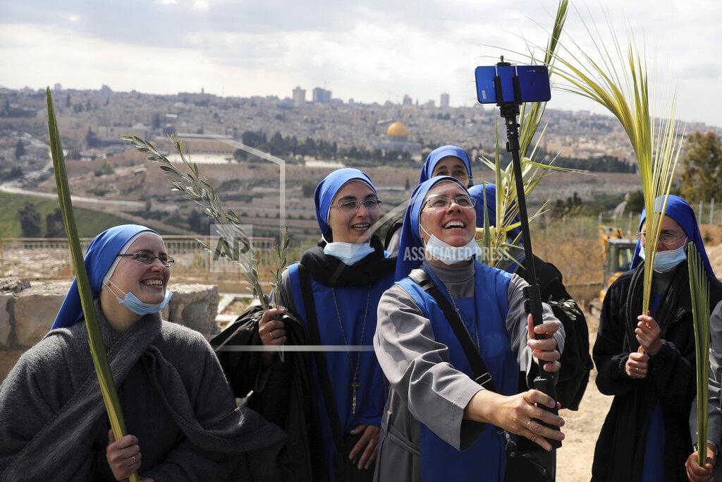 Nuns pose for a selfie as they mark Palm Sunday on the Mount of Olives in Jerusalem, Sunday, March 28, 2021. A year after coronavirus restrictions halted mass gatherings, Christians are celebrating Holy Week together. (AP Photo/Mahmoud Illean)