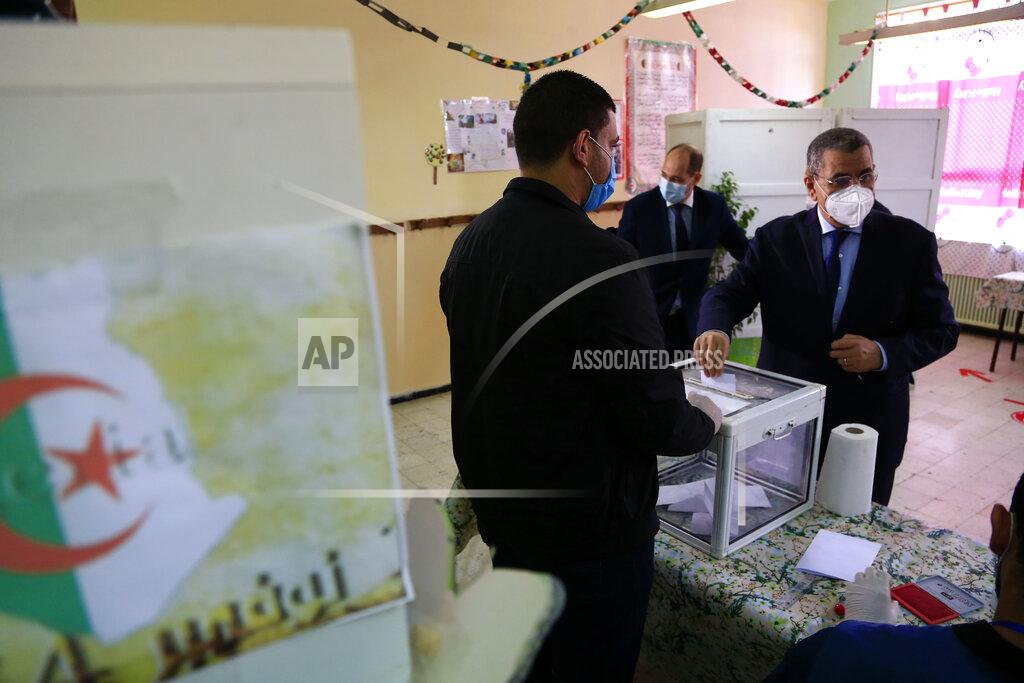 Toukik Doudou Algerian Prime Minister Abdelaziz Djerad, right, casts his ballot at a polling station during a vote for a revised constitution, in Algiers, Sunday, Nov. 1, 2020. Algerians are voting on whether to approve a revised constitution that imposes term limits and aims at answering demands from pro-democracy protesters who pushed out the president last year. (AP Photo/Toufik Doudou)