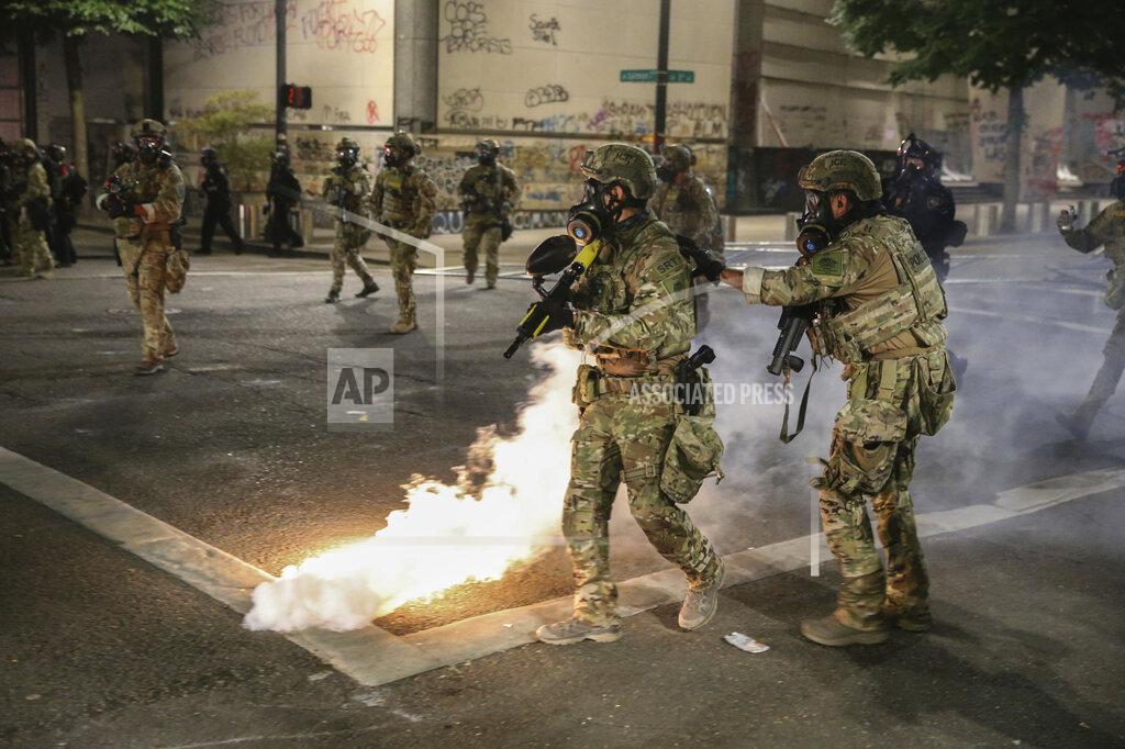 Dave Killen Police respond to protesters during a demonstration, Friday, July 17, 2020 in Portland, Ore. Militarized federal agents deployed by the president to Portland, fired tear gas against protesters again overnight as the city’s mayor demanded that the agents be removed and as the state’s attorney general vowed to seek a restraining order against them. (Dave Killen/The Oregonian via AP)