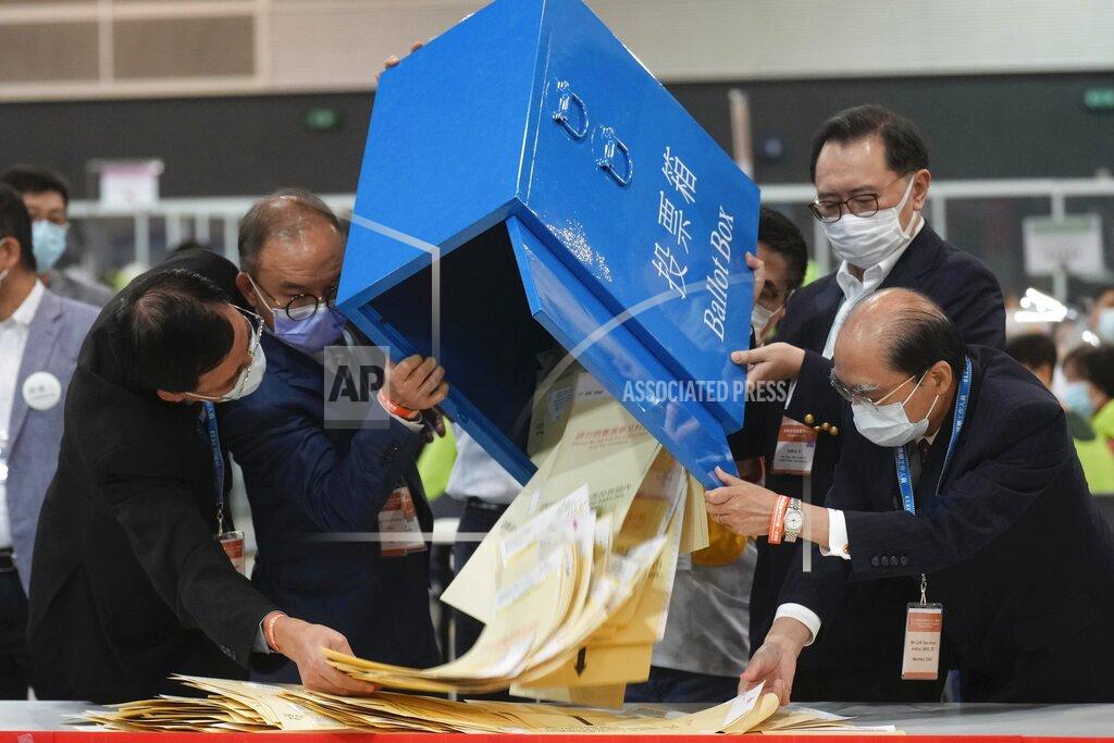 Vincent Yu Erick Tsang, second left, Secretary for Constitutional and Mainland Affairs Bureau, helps officials pour out ballots from a box at a counting center in Hong Kong, Sunday, Sept. 19, 2021. Select Hong Kong residents voted for members of the Election Committee that will choose the city's leader in the first polls Sunday following reforms meant to ensure candidates with Beijing loyalty. (AP Photo/Vincent Yu)