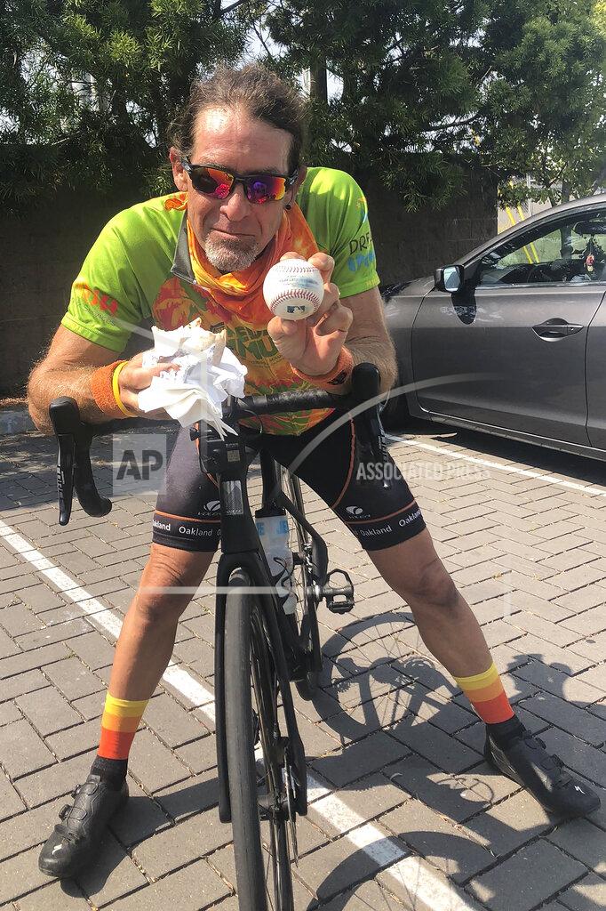 Janie Mccauley Avid baseball fan and cyclist Mark Pelzner poses with his foul ball, Sunday, Sept. 6, 2020, in Alameda, Calif. (AP Photo/Janie McCauley)