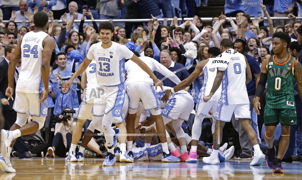 Gerry Broome North Carolina's Cameron Johnson (13) and Kenny Williams (24) celebrate with teammates following an NCAA college basketball game against Miami in Chapel Hill, N.C., Saturday, Feb. 9, 2019. North Carolina won 88-85 in overtime. Miami's Chris Lykes (0) walks away at right. (AP Photo/Gerry Broome)