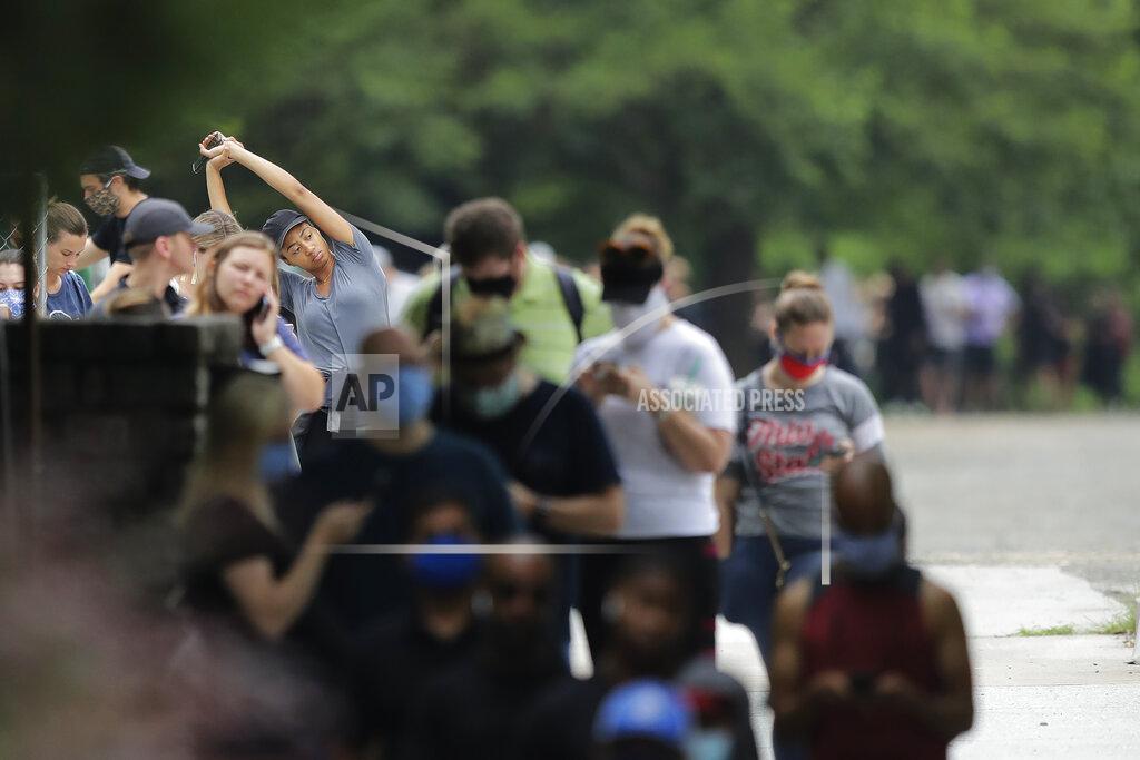 Brynn Anderson A person stretches as they wait in a line to vote in the Georgia's primary election at Park Tavern on Tuesday, June 9, 2020, in Atlanta. (AP Photo/Brynn Anderson)