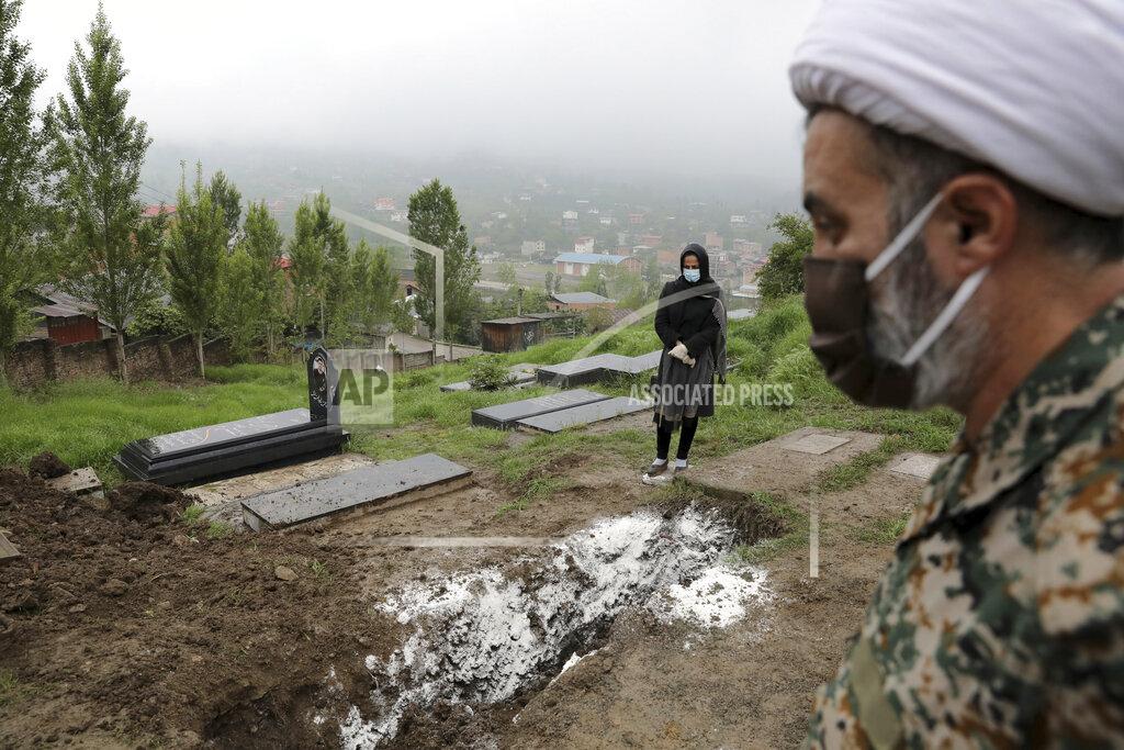 FILE - In this April 30, 2020 file photo, a woman wearing mask and gloves, prays at the grave of her mother who died from the new coronavirus, at a cemetery in the outskirts of the city of Babol, in northern Iran. Iranian state TV said Wednesday Oct. 7, 2020, that the country has hit its highest number of daily deaths from the coronavirus, with 239 new fatalities. Wednesday's report quotes the spokesperson of the country’s health ministry as saying the new deaths were recorded since Tuesday. (AP Photo/Ebrahim Noroozi, File)