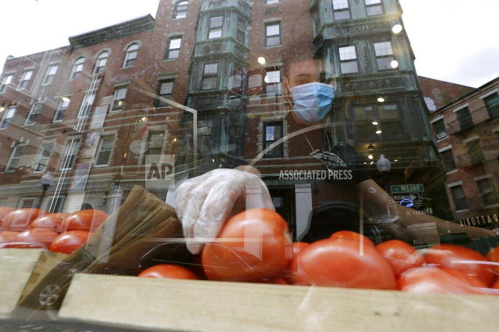 Steven Senne FILE - In this May 12, 2020 file photo, a worker places tomatoes in the window of Monica's Mercato & Salumeria food shop during the coronavirus pandemic, in the North End neighborhood of Boston. Small businesses can still get help from the government’s coronavirus relief plan after Congress extended the Paycheck Protection Program until Aug. 8. The program that had been set to expire last week still has more than $130 billion left after giving out more than 4.8 million loans since its April 3 start. (AP Photo/Steven Senne, File)