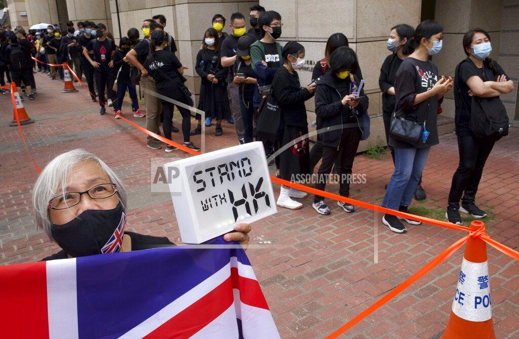 Vincent Yu FILE - In this Monday, March 1, 2021, file photo, a woman holds a placard and a U.K. flag, as supporters queue up outside a court to try to get in for a hearing of the 47 pro-democracy activists taken to court on charges of conspiracy to commit subversion under the national security law in Hong Kong. In the semi-autonomous city of Hong Kong, China is moving to eliminate the possibility of opposition politicians gaining office, saying only patriots loyal to the Communist Party can have a role in government. (AP Photo/Vincent Yu, File)