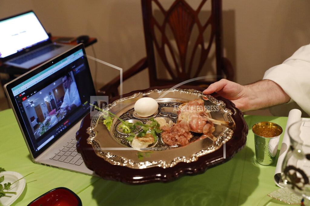 Kathy Willens Rabbi Shlomo Segal holds a ritual seder plate in front of a computer screen while conducting a virtual Passover seder and broadcasting it on YouTube for his congregants, friends and family members in the Sheepshead Bay section of Brooklyn during the current coronavirus outbreak, Wednesday, April 8, 2020, in New York. The new coronavirus causes mild or moderate symptoms for most people, but for some, especially older adults and people with existing health problems, it can cause more severe illness or death. (AP Photo/Kathy Willens)