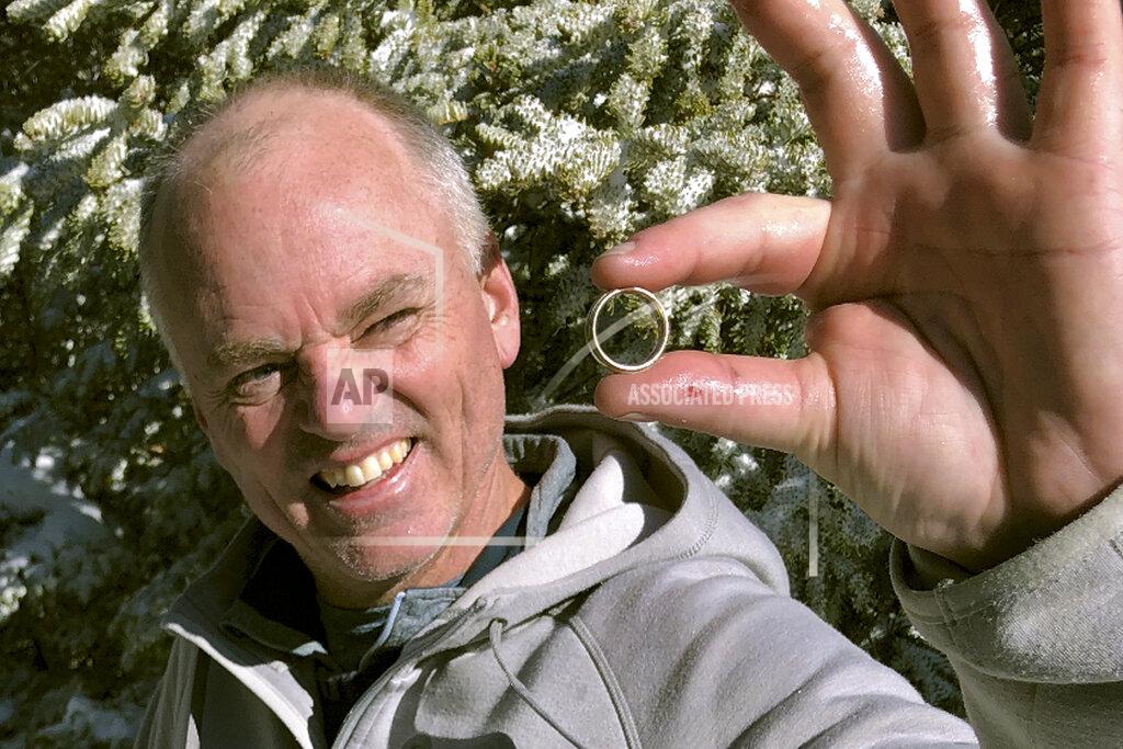 CORRECTS DATE TO NOV. 23, INSTEAD OF NOV. 13 - In this Nov. 23, 2019, photo provided by Brendan Cheever, Tom Gately holds a gold wedding band he found by using a metal detector on snow-covered Mount Hancock in New Hampshire's White Mountains. Bill Giguere, of North Andover, Mass., had been wearing the ring for three years and put out a plea to a hiking group for help after he lost it while hiking the previous week. (Brendan Cheever via AP)