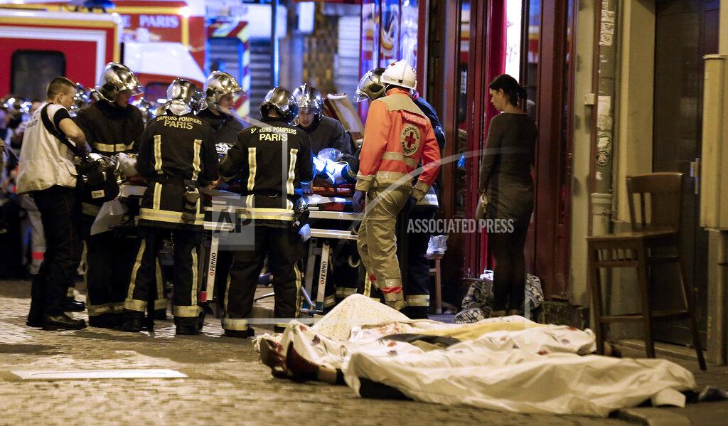 Jacques Brinon FILE - In this Nov.13, 2015 file photo, medics stand by victims in a Paris restaurant, Friday, Nov. 13, 2015. On Nov. 13, 2015, a cell of nine Islamic State militants armed with automatic rifles and explosive vests left a trail of dead and injured at the national stadium, Paris bars and restaurants and the Bataclan concert hall. Nearly all the attackers were from France or Belgium, as were the cell's 10th member — the only one still alive. He is the chief defendant among 20 people charged in a trial that is expected to last nine months. (AP Photo/Thibault Camus, File)