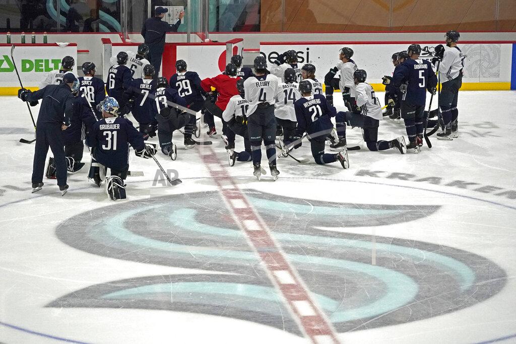 Ted S. Warren Seattle Kraken players kneel on the ice at their training facility as head coach Dave Hakstol outlines a play during NHL hockey practice, Thursday, Oct. 21, 2021, in Seattle. The Kraken will face the Vancouver Canucks, Saturday in Seattle for the expansion team's home opener. (AP Photo/Ted S. Warren)