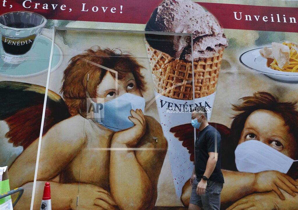 Vincent Yu A man wearing a face mask to prevent the spread of the coronavirus walks past a huge poster on a street in Hong Kong, Wednesday, May 12, 2021. (AP Photo/Vincent Yu)