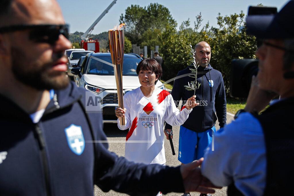 Thanassis Stavrakis Japanese Olympic marathon champion, Mizuki Noguch, center, the second torchbearer, holds the torch following the flame lighting ceremony at the closed Ancient Olympia site, birthplace of the ancient Olympics in southern Greece, Thursday, March 12, 2020, 2020. Greek Olympic officials are holding a pared-down flame-lighting ceremony for the Tokyo Games due to concerns over the spread of the coronavirus. Both Wednesday's dress rehearsal and Thursday's lighting ceremony are closed to the public, while organizers have slashed the number of officials from the International Olympic Committee and the Tokyo Organizing Committee, as well as journalists at the flame-lighting. (AP Photo/Thanassis Stavrakis)
