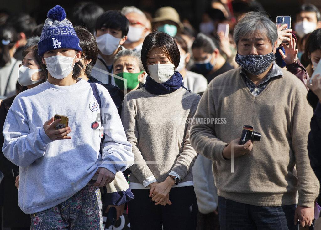 Hiro Komae One of the bystanders waiting at a traffic intersection closes her eyes when an annual tribute started at 2:46 p.m. for the victims of a 2011 disaster in Tokyo Thursday, March 11, 2021. Japan is marking the 10th anniversary Thursday of the earthquake, tsunami and nuclear disaster that hit the northeastern region. (AP Photo/Hiro Komae)