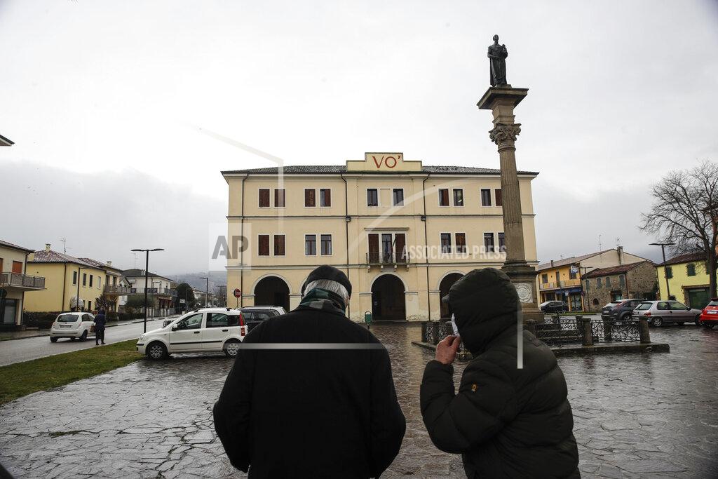 Luca Bruno People walk in front of the Vo Euganeo town hall, in Vo' Euganeo, northern Italy, Wednesday, Feb. 10, 2021. Shockwaves ran through the wine-making village of Vo, west of Venice, as word spread last Feb. 21 that a retired roofer had died of the new coronavirus becoming the first known COVID-19 victim in the West. (AP Photo/Luca Bruno)
