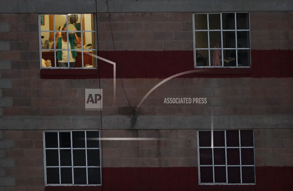Marco Ugarte A woman holds up a mirror as she brushes her hair inside her apartment in Mexico City, before sunrise Friday, May 8, 2020. Mexico woke up to news of its largest one-day increase in confirmed cases of COVID-19, from Wednesday to Thursday. (AP Photo/Marco Ugarte)