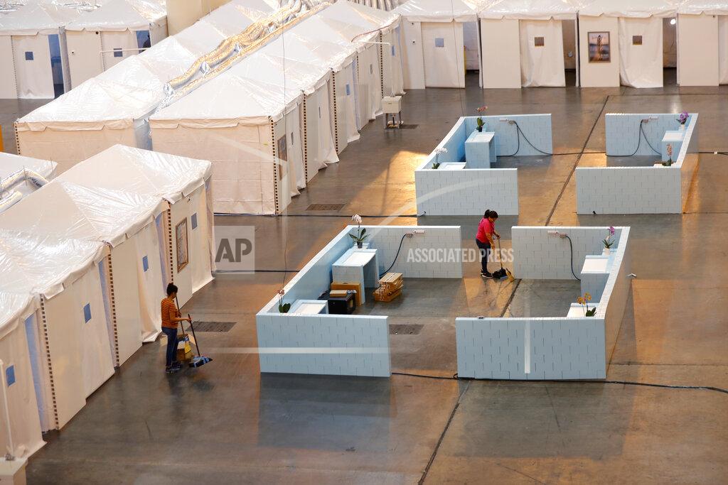Gerald Herbert FILE - In this April 4, 2020 file photo, workers sweeps inside a temporary hospital that has been set up in the Ernest N. Morial Convention Center, as overflow for local hospitals that are reaching capacity, in response to the COVID-19 pandemic, in New Orleans. Where political divides marred early recovery efforts after Hurricane Katrina in 2005, Louisiana is showing rare political unity in the fight against the new coronavirus. (AP Photo/Gerald Herbert, File)