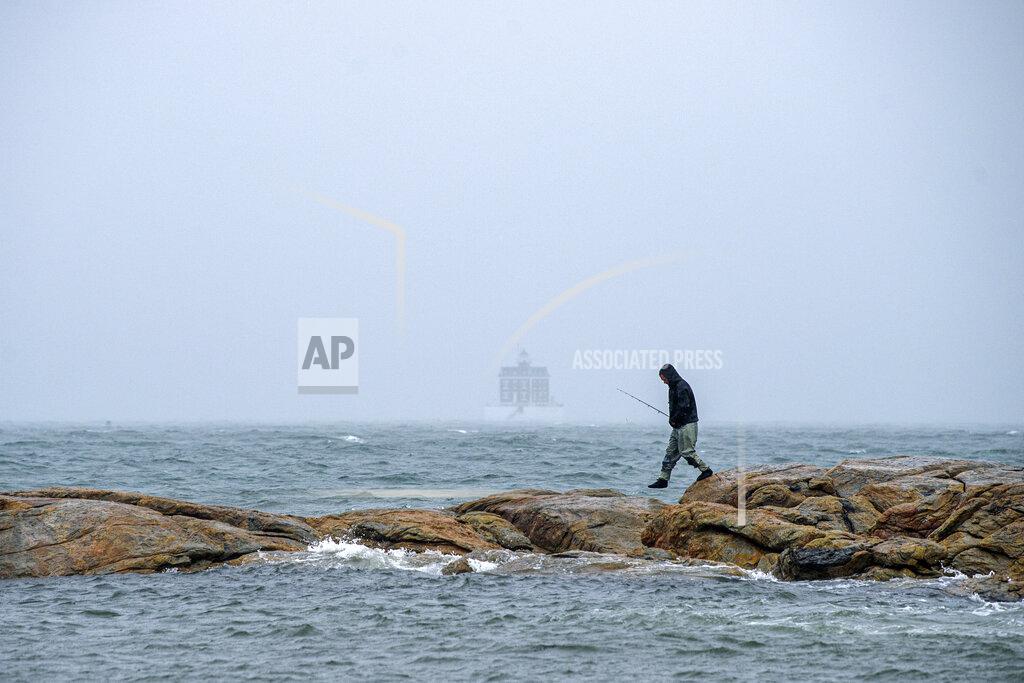 Mark Mirko Fisherman Adam Lurch fishes from the rocks off Eastern Point along the Long Island Sound in Groton, Conn., Tuesday, Oct. 26 2021, as a nor'easter is forecasted to bring heavy rain and strong winds. (Mark Mirko/Hartford Courant via AP)