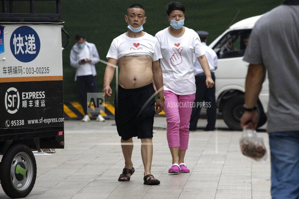 Ng Han Guan A couple wearing matching t-shirts and masks to curb the spread of the coronavirus walks along the street of Beijing on Thursday, June 11, 2020. (AP Photo/Ng Han Guan)