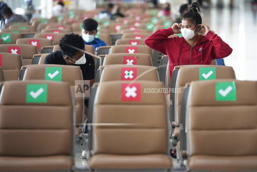 Sakchai Lalit Passengers sit spaced apart while wearing face masks to help curb the spread of the coronavirus at Suvarnabhumi airport in Bangkok, Thailand, Wednesday, July 21, 2021. The Civil Aviation Authority of Thailand has ordered a halt to all domestic flights operating from the most severely affected provinces effective Wednesday. Exceptions are allowed for flights to destinations that are part of a plan that allows vaccinated travelers from abroad to stay for two weeks on popular islands such as Phuket and Samui without quarantine confinement. (AP Photo/Sakchai Lalit)