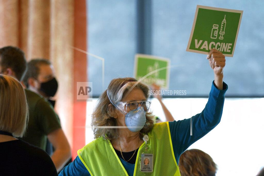 Ted S. Warren Sally Avenson, a nurse working as a volunteer at a mass vaccination clinic at Seattle University, holds up a sign to indicate she needs more doses of the Moderna COVID-19 vaccine at her station, Friday, Feb. 26, 2021, in Seattle. As states ramp up vaccination distribution in the fight against the coronavirus, volunteers are needed to do everything from direct traffic to check people in to keep vaccination sites running smoothly. (AP Photo/Ted S. Warren)