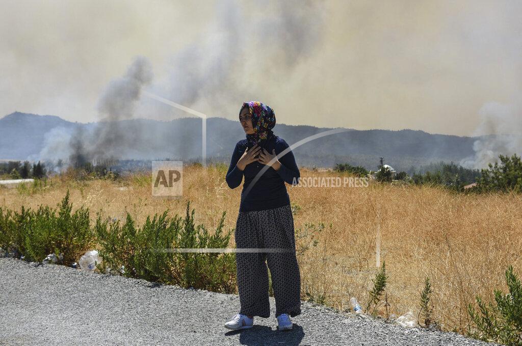 Uncredited A woman looks at the wildfires in Kacarlar village near the Mediterranean coastal town of Manavgat, Antalya, Turkey, Saturday, July 31, 2021. The death toll from wildfires raging in Turkey's Mediterranean towns rose to six Saturday after two forest workers were killed, the country's health minister said. Fires across Turkey since Wednesday burned down forests, encroaching on villages and tourist destinations and forcing people to evacuate.(AP Photo)