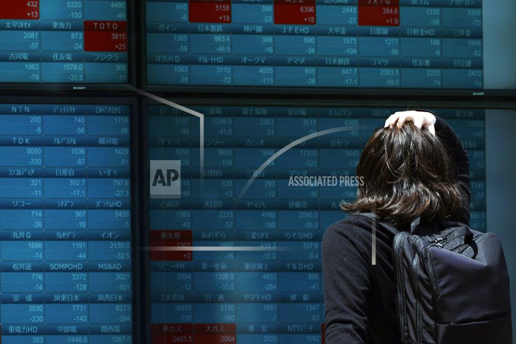 A man looks at an electronic stock board showing Japan's Nikkei 225 index at a securities firm in Tokyo Friday, May 1, 2020. Shares have dropped in Asia after Wall Street ended its best month in 33 years with losses on fresh news of economic carnage from the coronavirus pandemic. (AP Photo/Eugene Hoshiko)